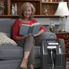 Image of DeVilbiss 1025 10 Litre Home Oxygen Concentrator in home setting beside seated user receiving oxygen