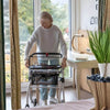 Image of Lightweight Indoor Rollator Walker with One Hand Brake in use by elderly woman indoors with tray and basket
