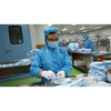 Image of Worker in protective clothing packing disposable face masks