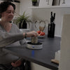 Image of Wheelchair user opening a tin one-handed at the kitchen bench with the Easy-Up holding it steady