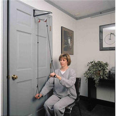 Woman seated using the Rolyan Reach N' Range overhead shoulder pulley on a door